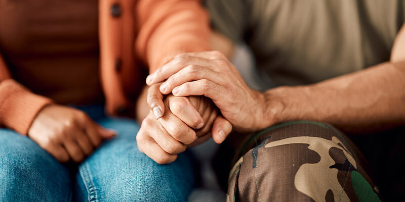 Mann und Frau sitzen nebeneinander und halten sich die Hände